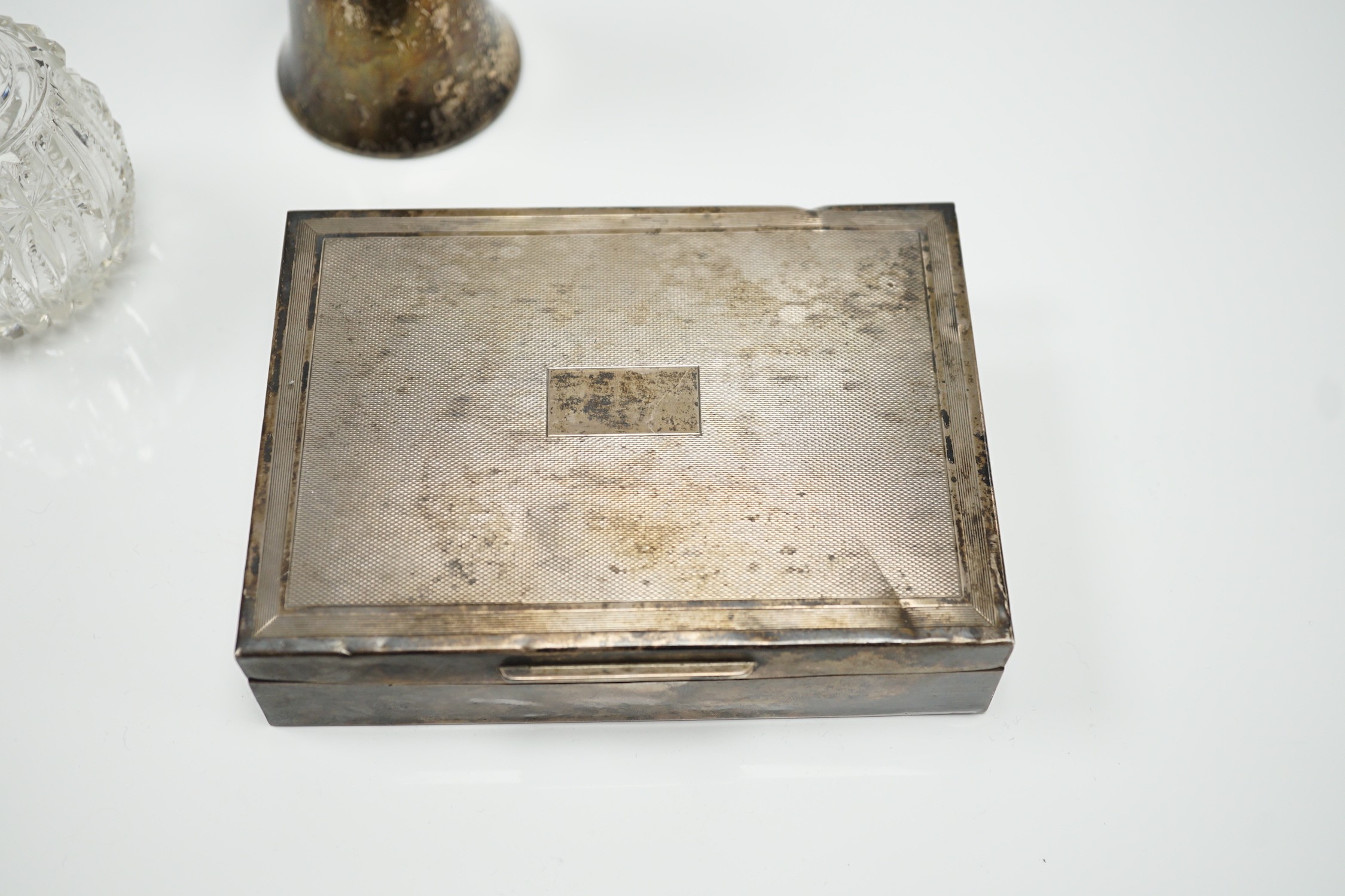 A 1970's engine turned silver mounted rectangular cigarette box, a silver mounted glass sugar caster and a similar scent bottle.